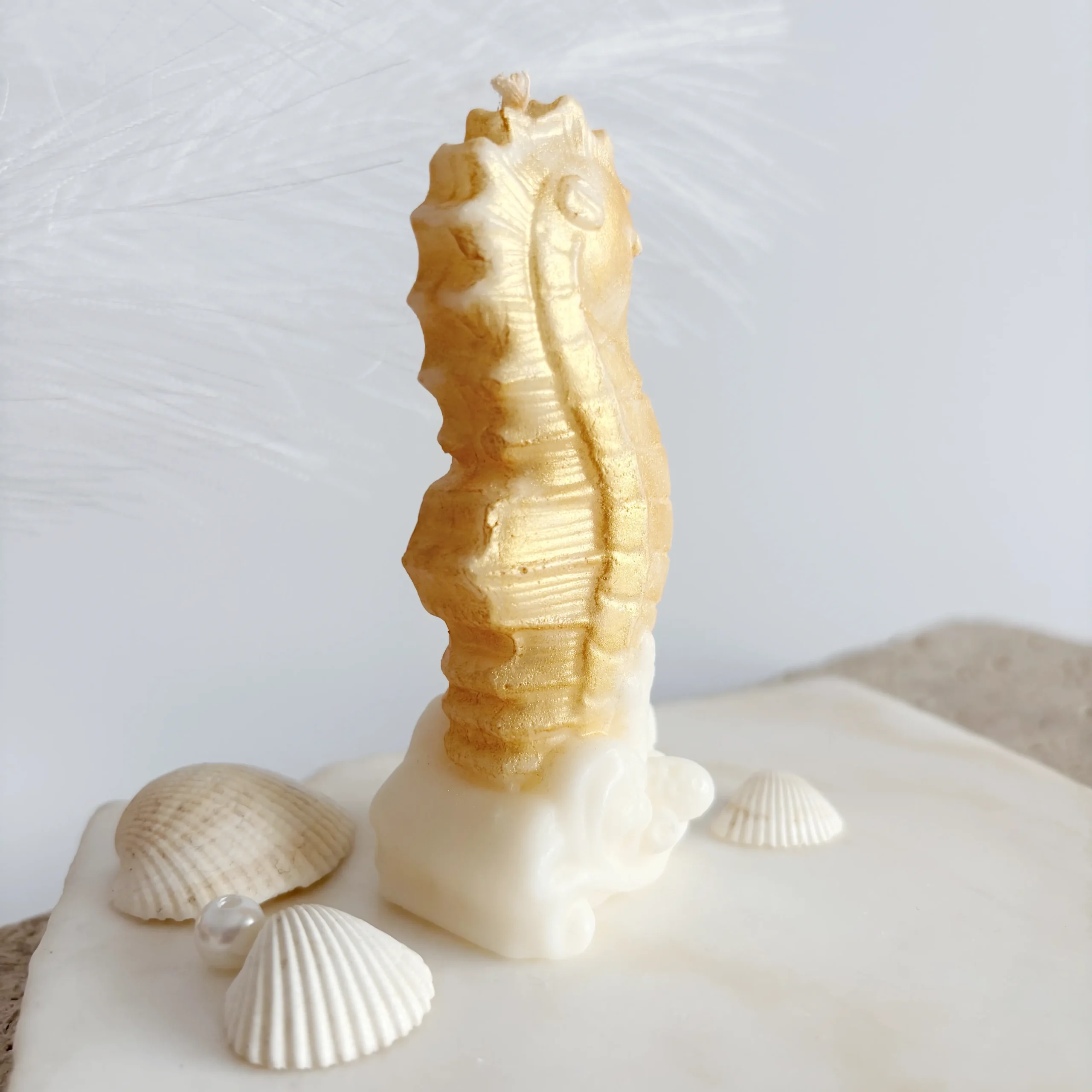 vedere din spate - căluț de mare lumânare parfumată auriu pe coral