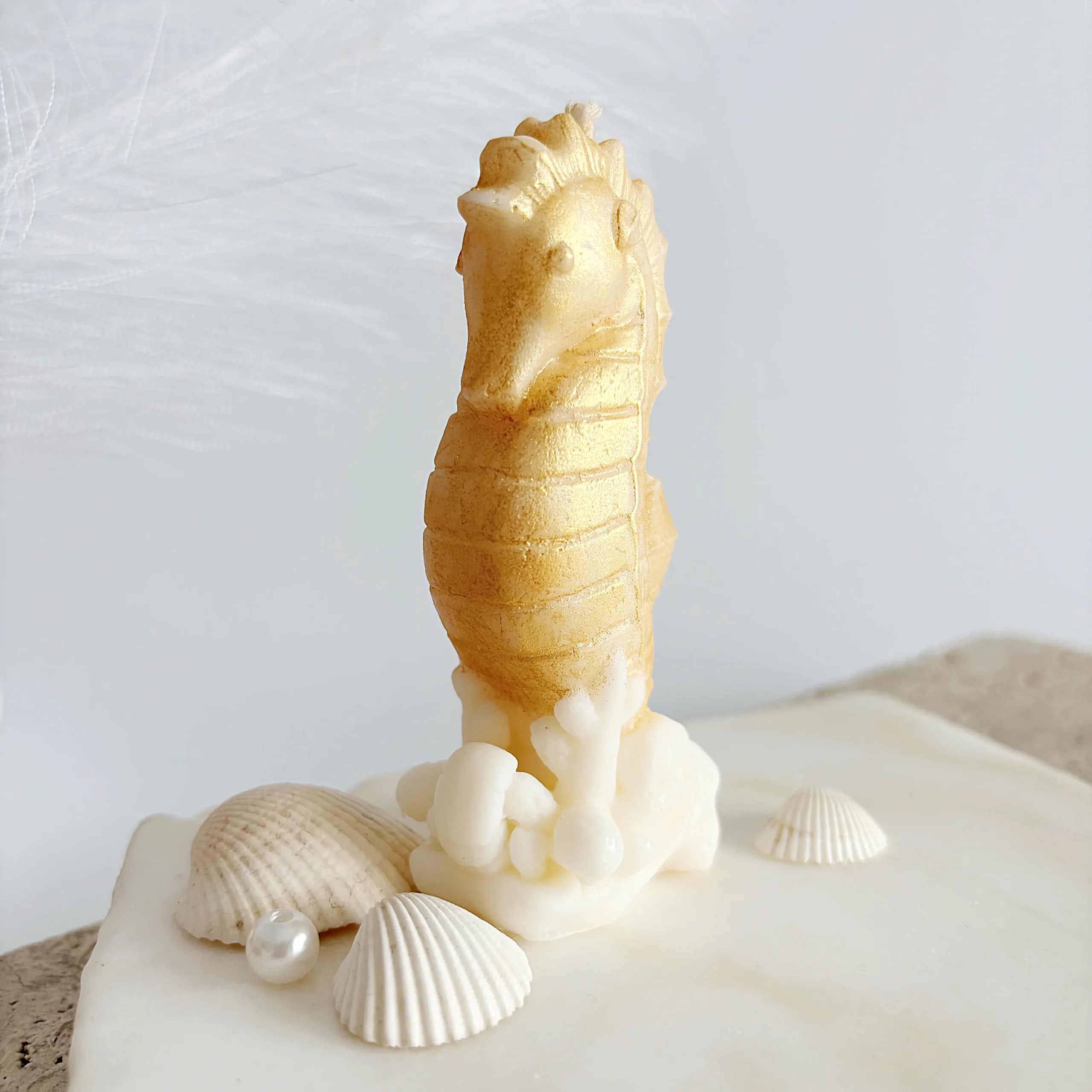 vedere frontală oblică lumânare parfumată decorativă - căluț de mare auriu pe coral