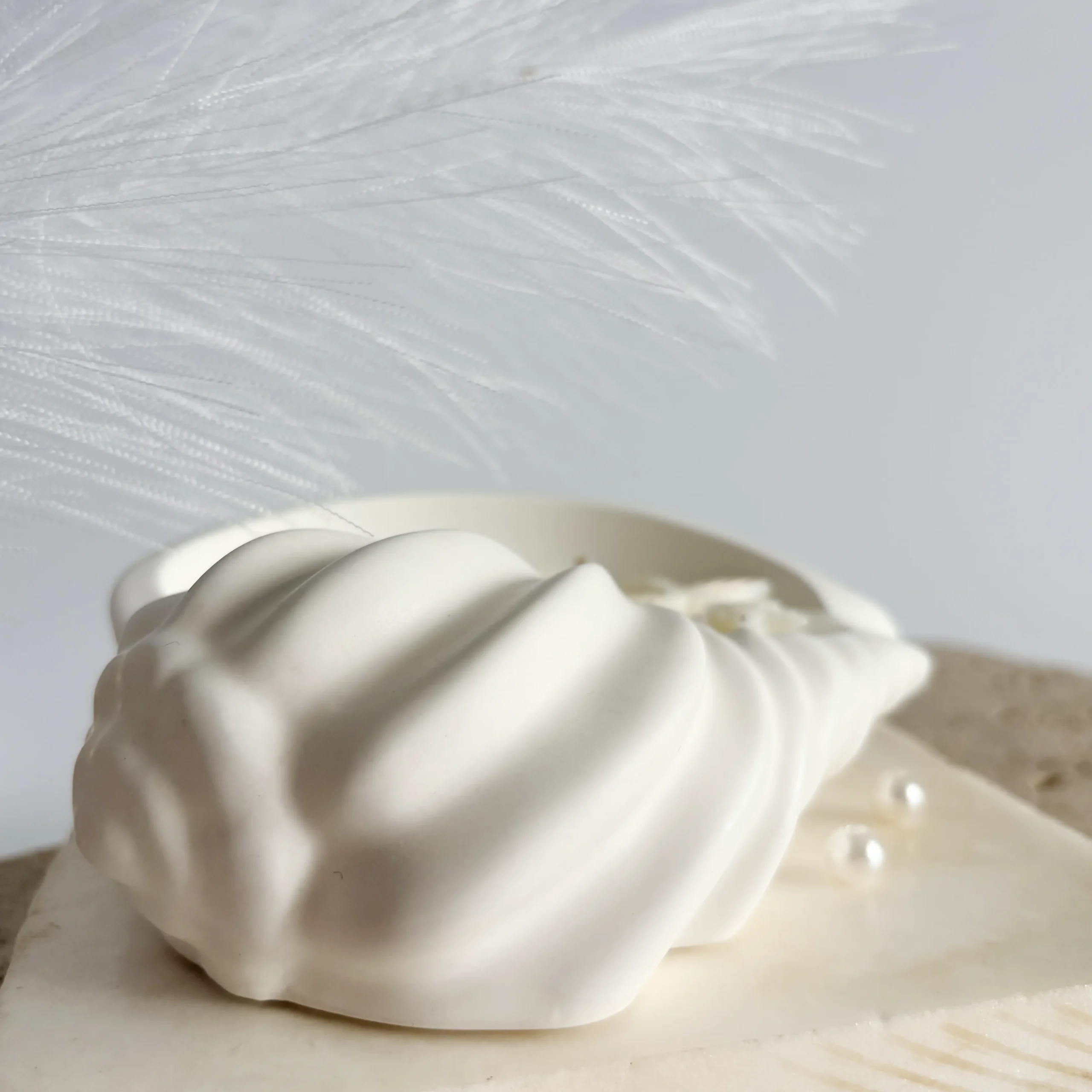 Perspectivă laterală lumânare parfumată în formă de scoică în vas ceramic