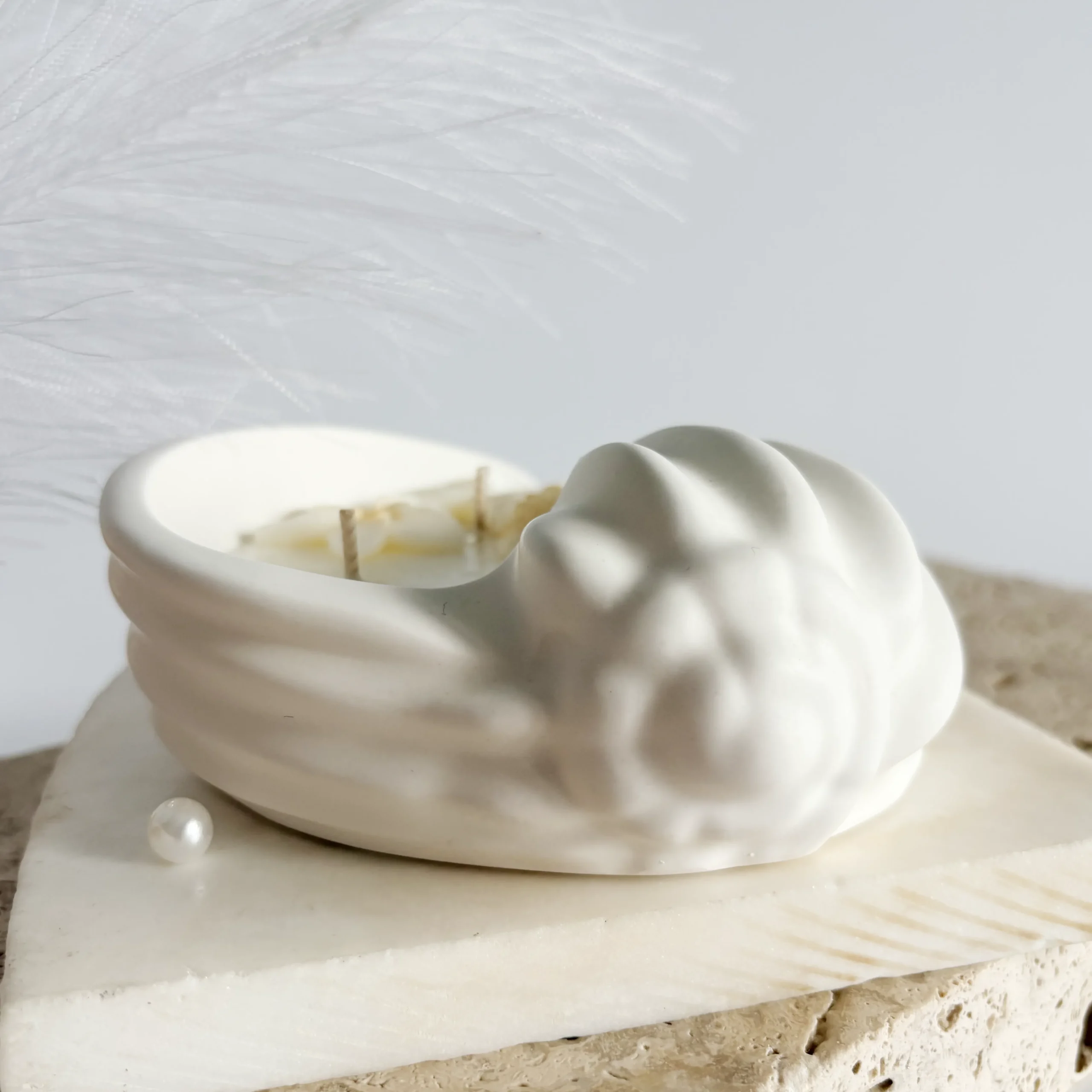 perspectivă frontală lumânare în vas ceramic în formă de scoică albă